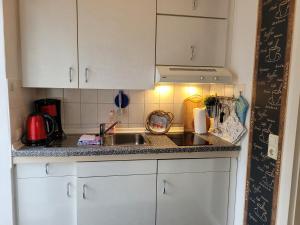 a kitchen counter with a sink and white cabinets at Ferienwohnung Mira in Cottbus