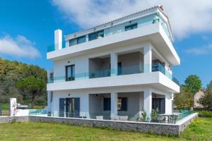 una casa blanca con muchas ventanas en Mythos Luxury Villa-Skiathos en Troulos