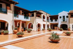 a courtyard of a building with potted plants at Nicolaus Club Torre Moresca in Cala Liberotto