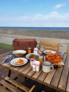 PICNIC　GARDEN في Awaji: طاولة نزهة مع الطعام والمشروبات والشاطئ