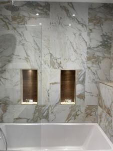 a bathroom with a white tub and a marble wall at Park Avenue Hotel in London