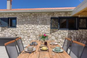 einen Holztisch mit Stühlen und eine Steinmauer in der Unterkunft Private Villa Bosilen Marina by Trogir Split airport Sibenik in Marina