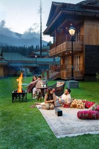 un grupo de personas sentadas en la hierba junto a un fuego en The Khyber Himalayan Resort & Spa en Gulmarg