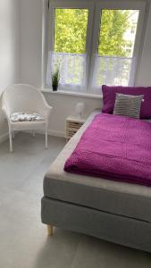 a bedroom with a purple bed and a chair at Villa Mariensiel in Sande