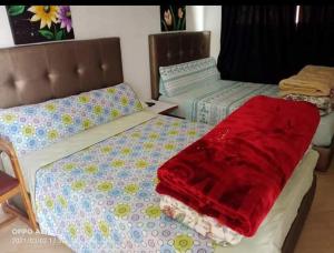 Dos camas en una habitación con una manta roja. en دوار ابغاوة ازغيرة تروال سد الوحدة وزان, en Srija