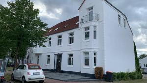 a white house with a car parked in front of it at Villa Mariensiel in Sande