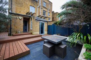 a wooden patio with a bench in front of a building at The Southwark Townhouse - Adorable 3BDR House with Garden in London