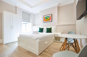 a white bedroom with a bed and a table at Woodview Serviced Apartments by Concept Apartments in London