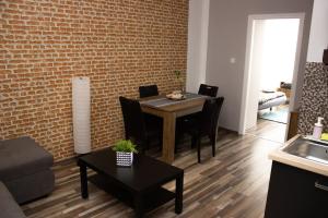 a living room with a table and chairs and a brick wall at Broadway Apartments B2 in Debrecen