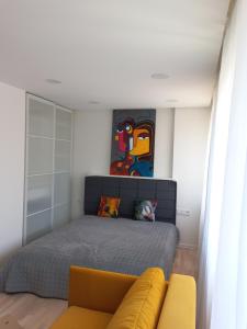 um quarto com uma cama e um sofá amarelo em Vėtrungė center apartment em Klaipėda