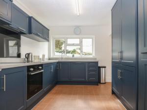 a kitchen with blue cabinets and a sink and a window at Dolafon in Pwllheli