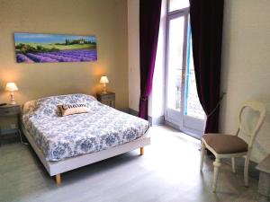 コルド・シュル・シエルにあるLe Relais Bastide de Cordes sur Cielのベッドルーム1室(ベッド1台付)、紫色の花の窓が備わります。