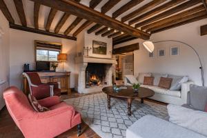 een woonkamer met een bank en een open haard bij Maison "Jardin Gaillard" in Biéville-en-Auge