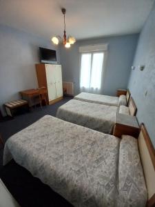 a hotel room with two beds and a window at Hôtel Hélios in Lourdes