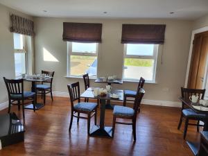 a dining room with tables and chairs and windows at Dunquin House Bed and Breakfast in Dunquin