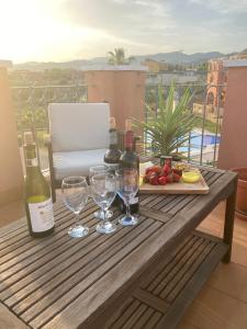 a table with wine bottles and glasses on a balcony at Penthouse Mojon Hills in Isla Plana