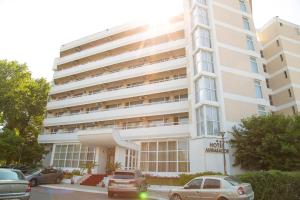 a large white building with cars parked in front of it at Hotel Ambasador in Mamaia