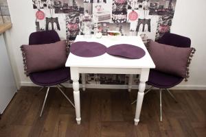 una mesa blanca con tres sillas púrpuras alrededor en Broadway Apartments B1 en Debrecen