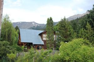 a wooden house with a fence and mountains in the background at ChacraKremen in El Bolsón