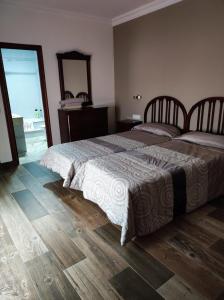 a bedroom with two beds and a wooden floor at Casa Hormaza in Chiclana de la Frontera
