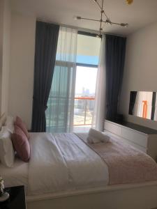 a bedroom with a large bed with a large window at Hayyak Homes-Luxury 1 bedroom Apartment in Dubai