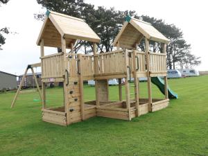 a wooden playset with a slide in a park at Seahorse Retreat in Haverfordwest