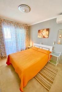 LuxBenidorm في بنيدورم: غرفة نوم مع سرير برتقالي كبير ونافذة