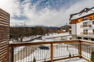 a balcony with a view of a snow covered street at VacationClub – Cristal Resort Apartament 222 in Szklarska Poręba