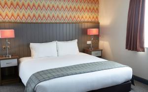 uma cama grande num quarto de hotel com duas lâmpadas em New Inn by Greene King Inns em Newport