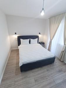 a bedroom with a white bed and a wooden floor at TEILOR Apartments 5 in Floreşti