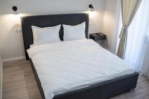1 dormitorio con 1 cama grande con sábanas y almohadas blancas en TEILOR Apartments 5, en Floreşti