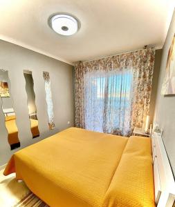 um quarto com uma cama amarela e uma janela em LuxBenidorm em Benidorm