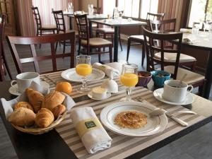 una mesa con alimentos para el desayuno y zumo de naranja en ella en Le Petit Keriquel, en La Chapelle-Caro
