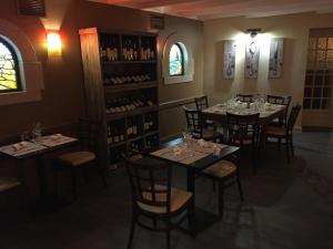 a dining room with tables and chairs and wine bottles at Le Petit Keriquel in La Chapelle-Caro