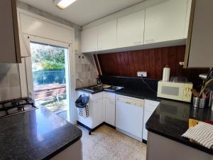 una cocina con armarios blancos y encimeras negras en Can Nitu, en Camprodon