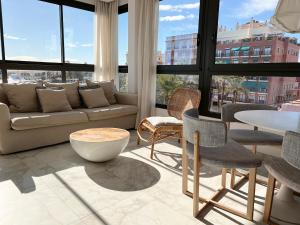 Valencia Luxury - Calma Beach Apartments في فالنسيا: غرفة معيشة مع أريكة وطاولة وكراسي