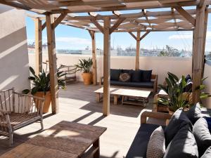 een patio met een bank en een houten pergola bij Valencia Luxury - Calma Beach Apartments in Valencia