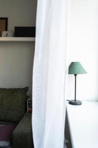 uma cortina branca ao lado de um sofá e um candeeiro em In between center and sea appartment em Liepāja