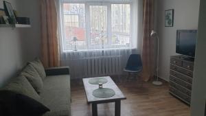 uma sala de estar com um sofá, uma mesa e uma televisão em In between center and sea appartment em Liepāja