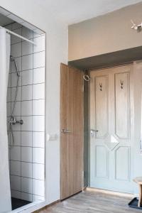 uma casa de banho com um chuveiro e uma porta de madeira em In between center and sea appartment em Liepāja