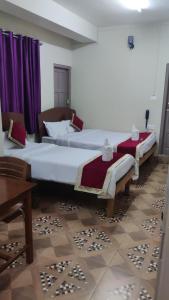 2 camas en una habitación con cortinas moradas en Magvaris Comfort Inn, en Shillong