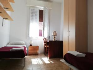 um quarto com 2 camas, uma secretária e uma janela em Appartamento: tranquillità o divertimento em Bolonha
