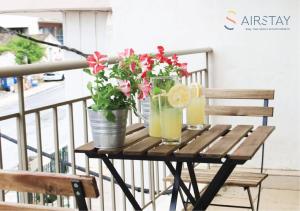 einen Holztisch mit Getränken und Blumen auf dem Balkon in der Unterkunft Anivia Apartments Airport by Airstay in Spáta