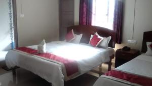 1 dormitorio con 2 camas con sábanas blancas y almohadas rojas en Magvaris Comfort Inn, en Shillong