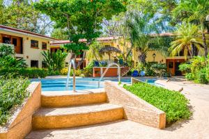 un complejo con una piscina con escaleras y árboles en Cocomarindo#73, en Coco