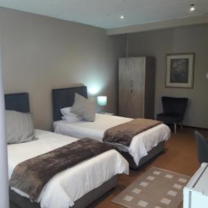 um quarto de hotel com duas camas e uma cadeira em Whispering Pines Country Estate em Magaliesburg