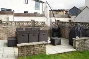 a patio with chairs and an umbrella on a brick fence at Bryn Derwen in Caernarfon