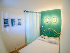een slaapkamer met een bed met een groene muur bij Splendide appartement GOLDEN HOUSE vue LAC et montagne in Port-la-Nouvelle