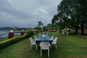 una mesa con sillas blancas, una mesa azul y un sillón en Shree Vilas Orchid By Lake Pichhola, en Udaipur