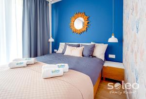 a blue bedroom with two beds and a mirror at Apartament Dwupoziomowy SUPERIOR z 2-sypialniami i klimatyzacją - SOLEO Family Resort in Rewal